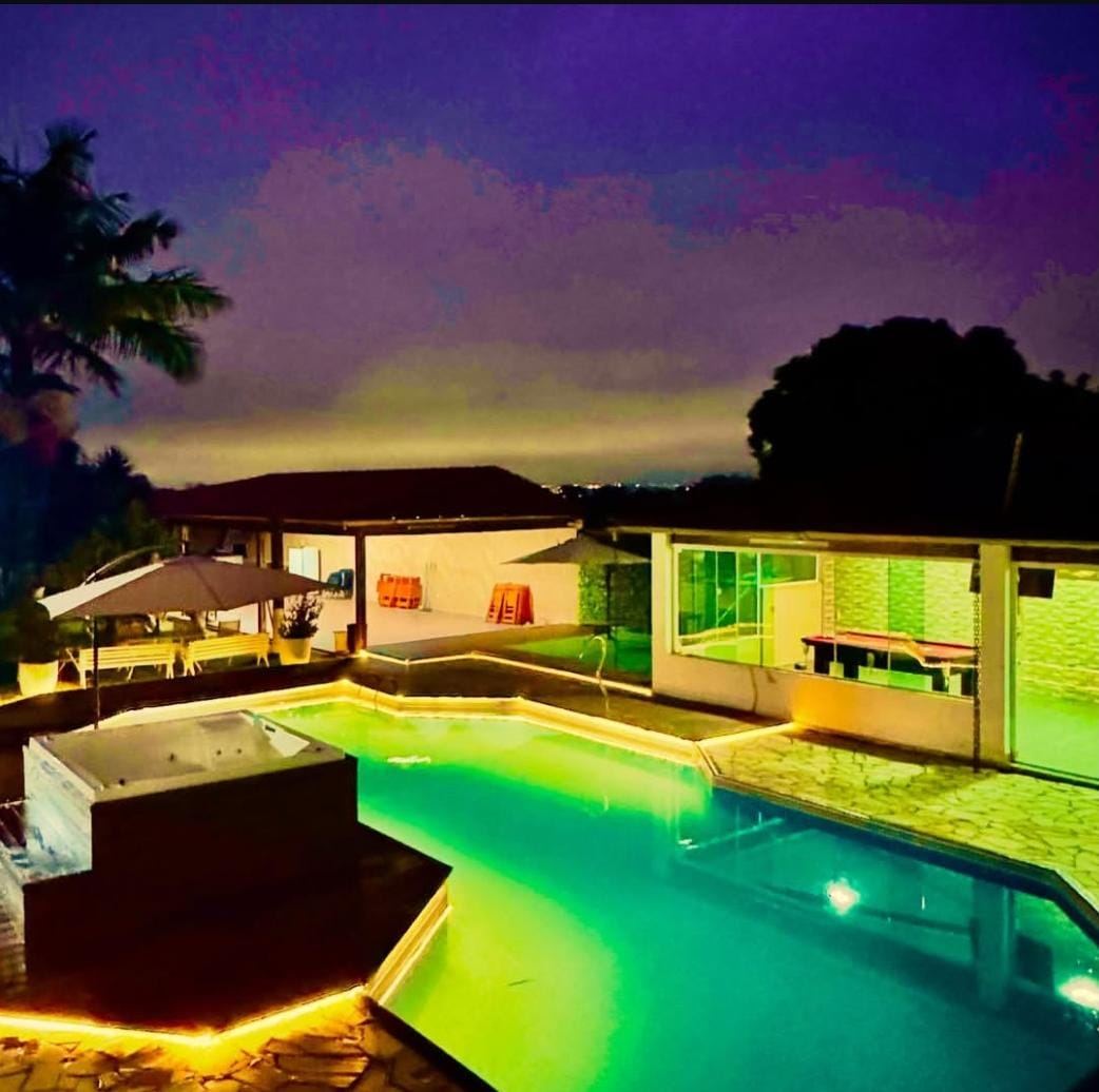 Piscina iluminada da Chácara Pellaro ao entardecer